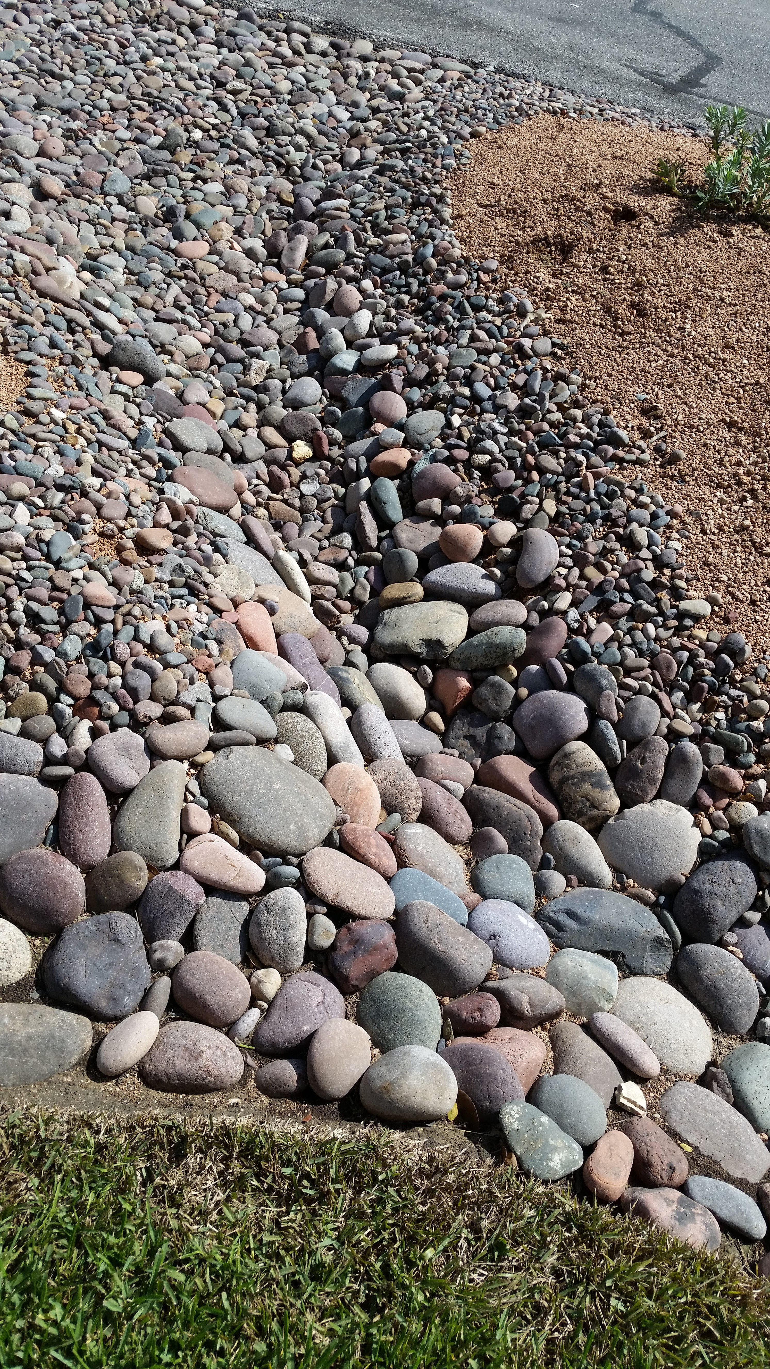 River rock dry creek bed, showcasing larger rocks and varied sizes for a naturalistic and functional landscape feature.