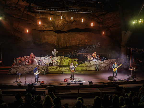 Wide shot of Lord Huron performing on stage at Red Rocks Amphitheater from ticketed seats in row 9, showing the stage setup and crowd.