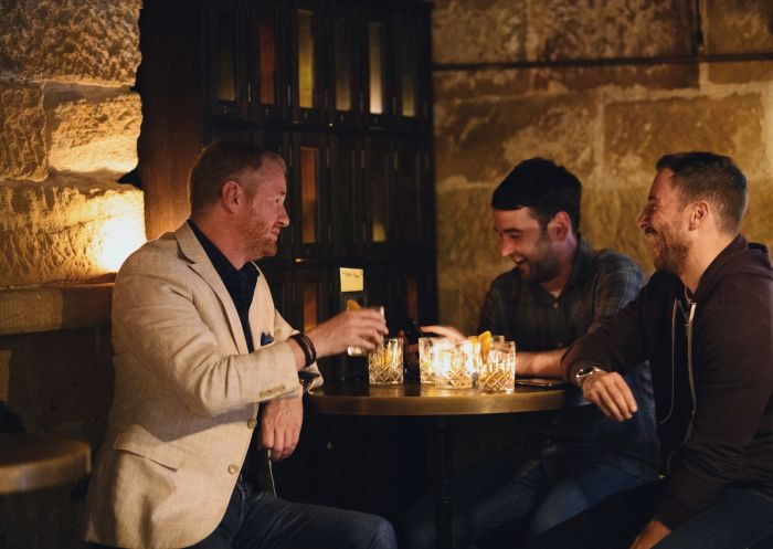 The dimly lit interior of The Doss House whisky bar in The Rocks, Sydney, highlighting its heritage ambiance and selection of spirits.