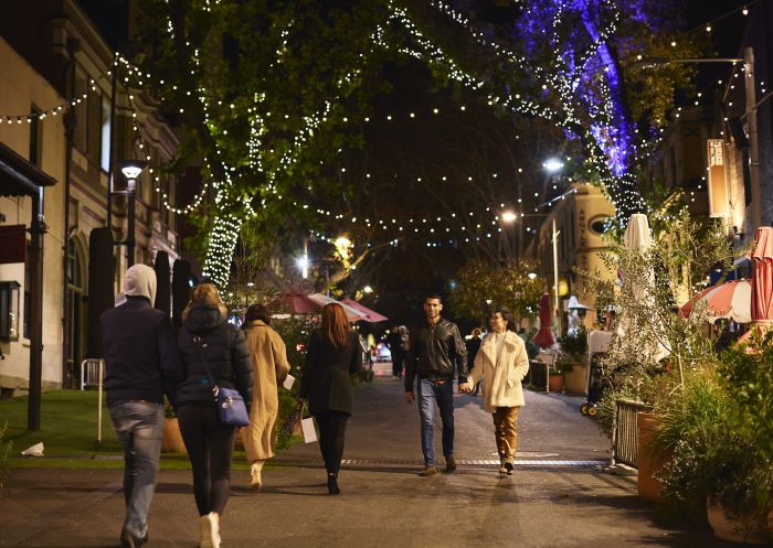 Night scene in The Rocks, Sydney, showcasing illuminated heritage buildings and a lively street filled with people.