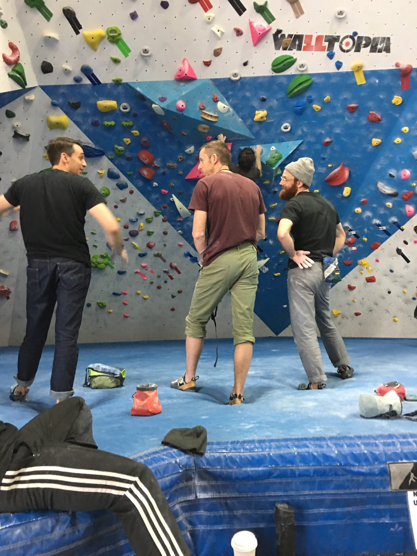 A climber reaching the top of a wall at The Cliffs, highlighting the height and challenge of rock climbing gyms in NYC.