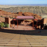 Panoramic view of Red Rocks Amphitheatre showcasing the stage nestled between towering red rock formations and the distant Denver skyline.