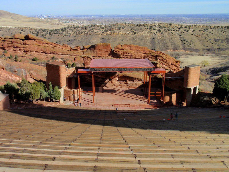 Panoramic view of Red Rocks Amphitheatre showcasing the stage nestled between towering red rock formations and the distant Denver skyline.