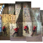 Enthusiastic climber ascending the vibrant 37-foot rock climbing wall at UMPI's Gentile Hall, showcasing the facility's exciting and accessible climbing experience.