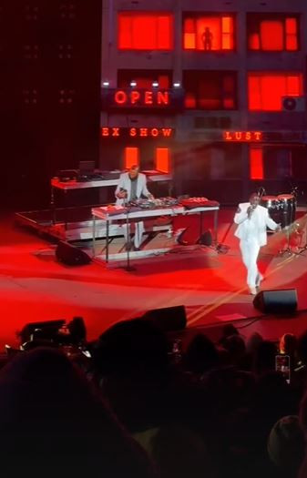 alt text of akon performing on stage at red rocks with bright lights and the crowd visible in the background.