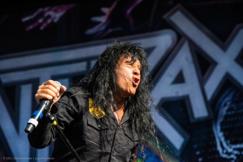 Joey Belladonna of Anthrax singing at Blue Ridge Rock Festival Day 2. The Anthrax vocalist is passionately singing into the microphone, engaging the audience.