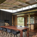 Interior dining area of Castle Rock Beach House featuring wooden table and chairs, emphasizing natural light and connection to outdoor views