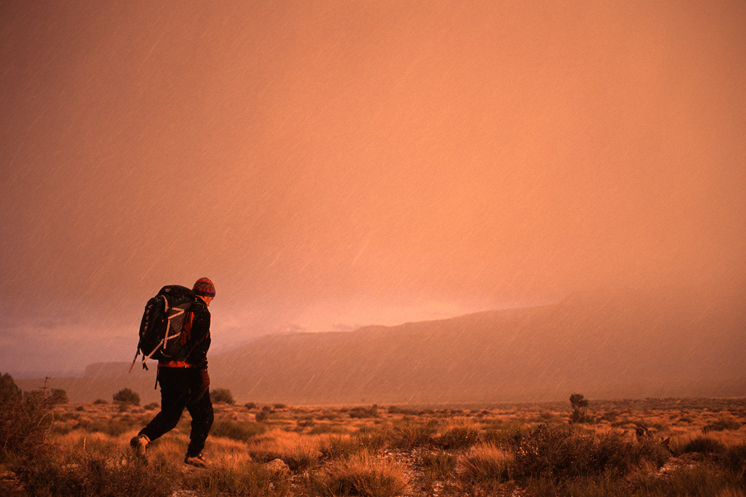 A person hiking in a wilderness area with stacked rocks visible