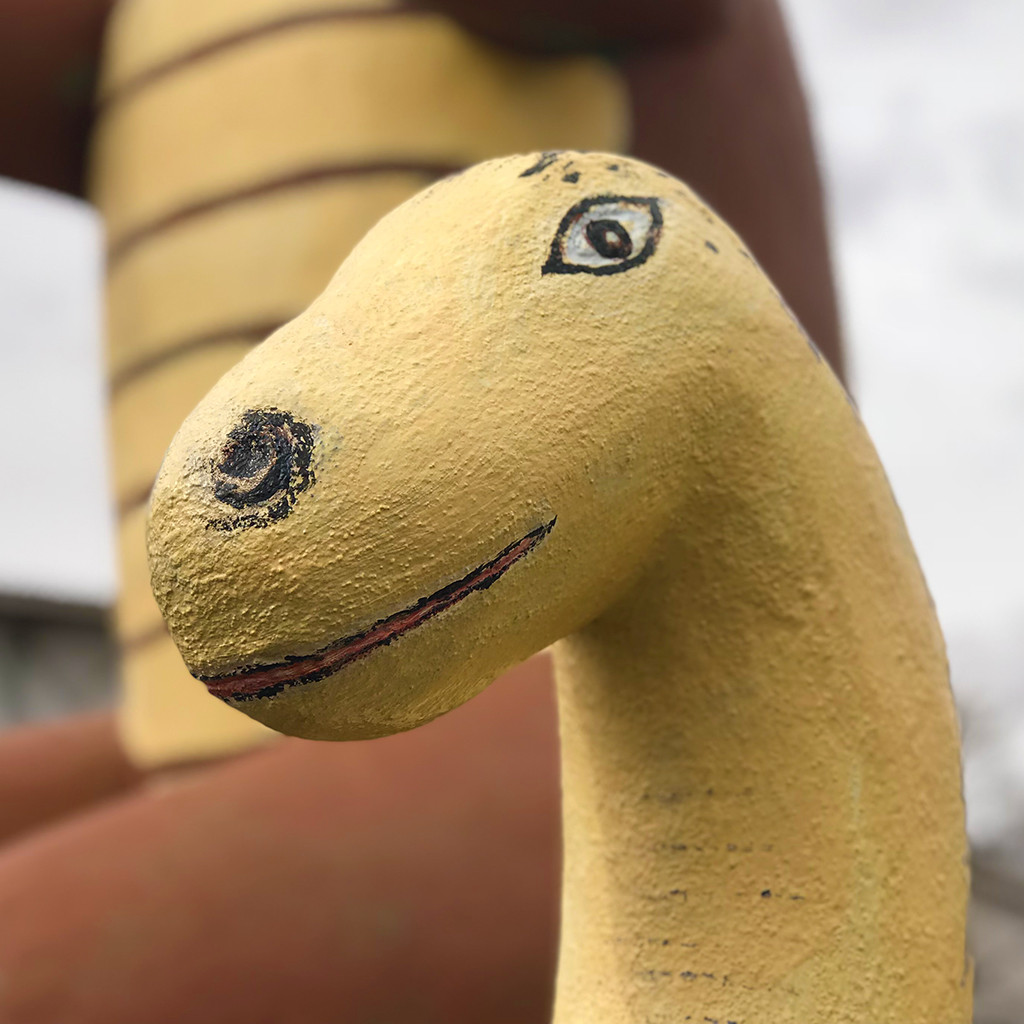 Several cement dinosaur statues standing in front of the Rainbow Rock Shop in Holbrook, Arizona, under a sunny sky