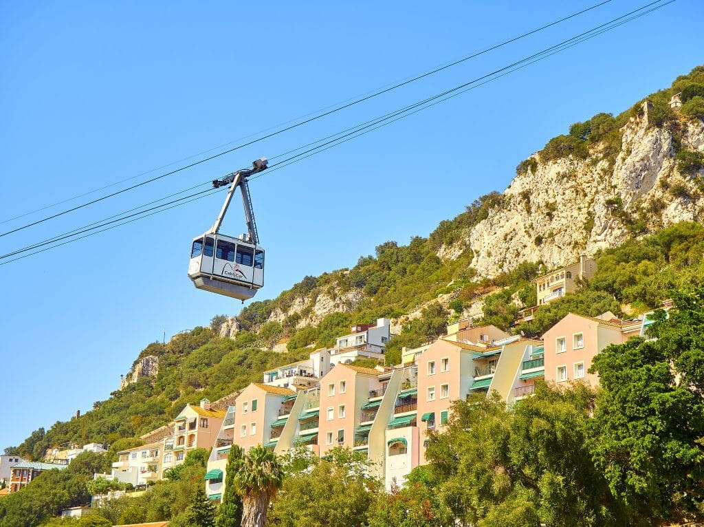 Gibraltar Cable Car ascending the Rock, with a view of the city and surrounding sea in the background.