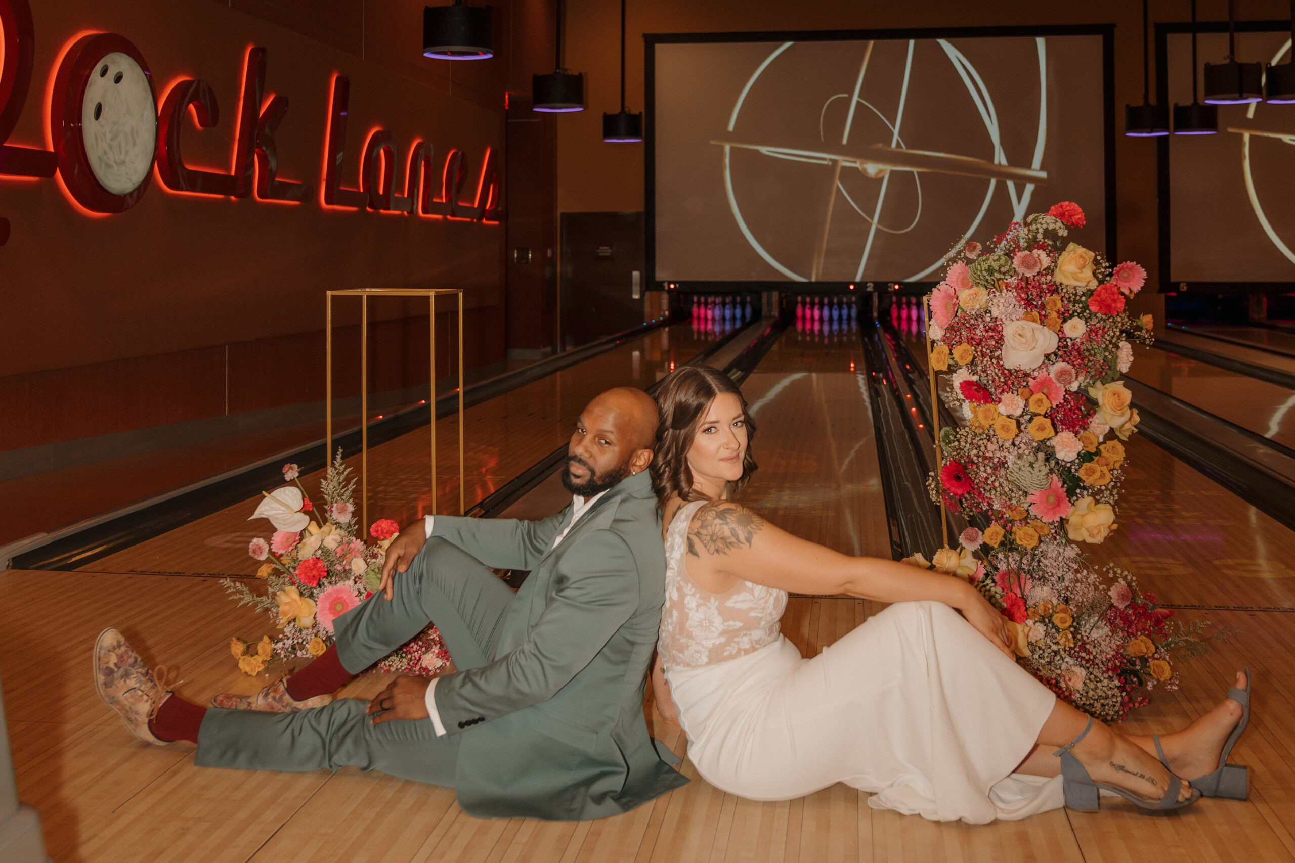 Wide shot of bride and groom posing on bowling lanes at Red Rock Lanes