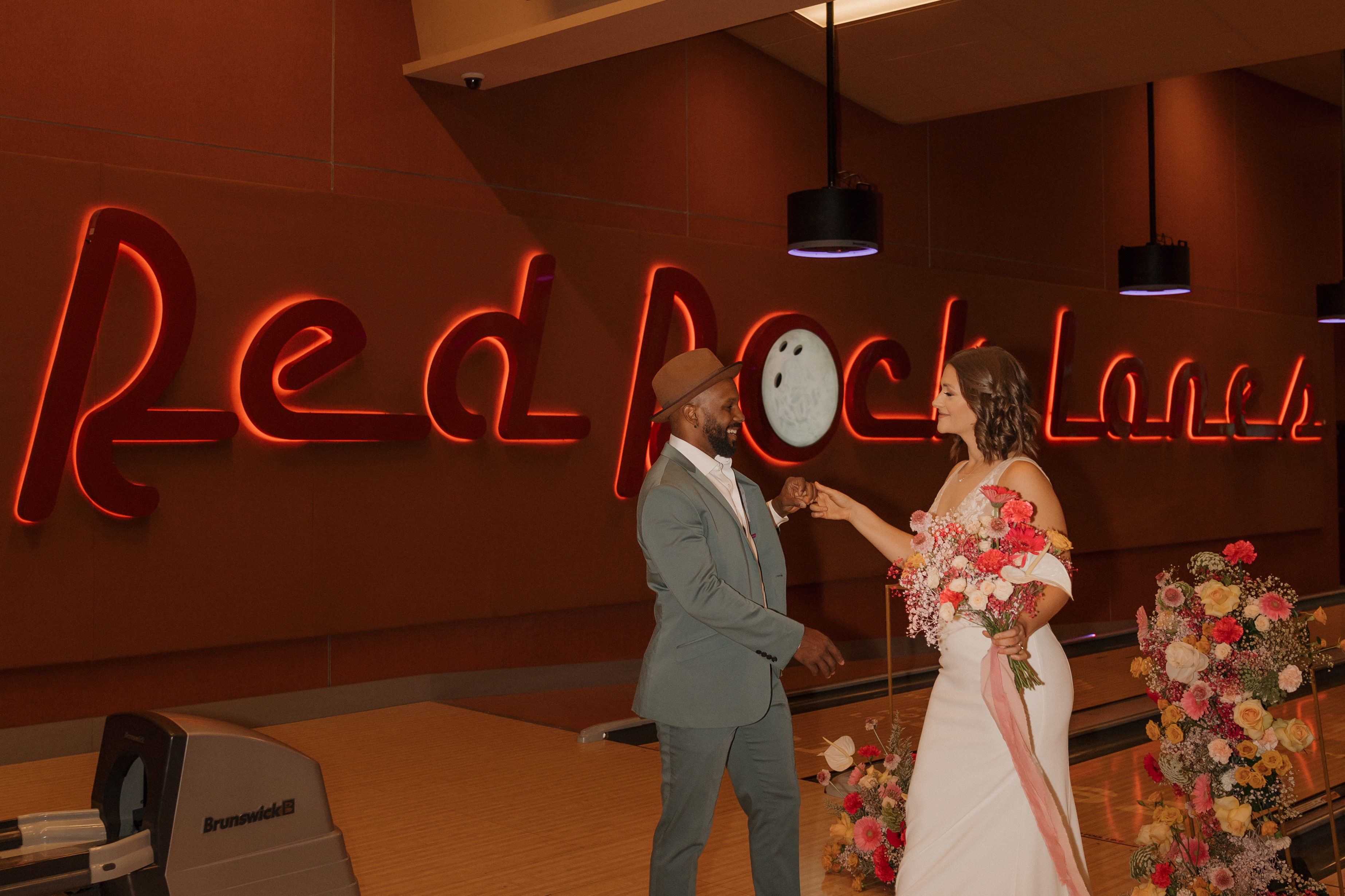 Eloping couple sharing a kiss and holding bowling ball at Red Rock Lanes