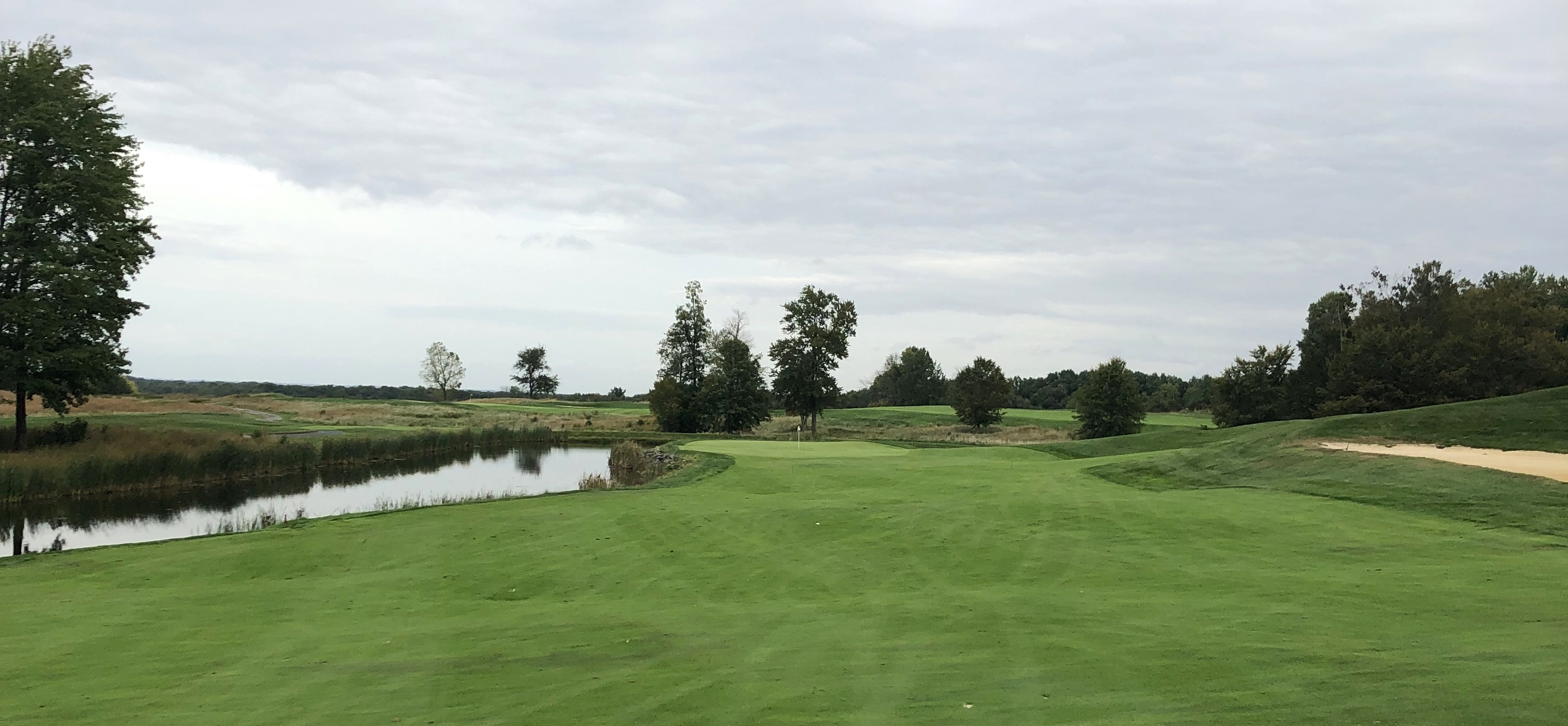 The approach to the 18th green at Bulle Rock Golf, highlighting the intimidating water hazard and strategically placed bunkers.