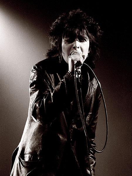 Siouxsie Sioux performing in her iconic style, alt text: Siouxsie Sioux, gothic rock icon, performs with her signature dramatic style and powerful vocals.