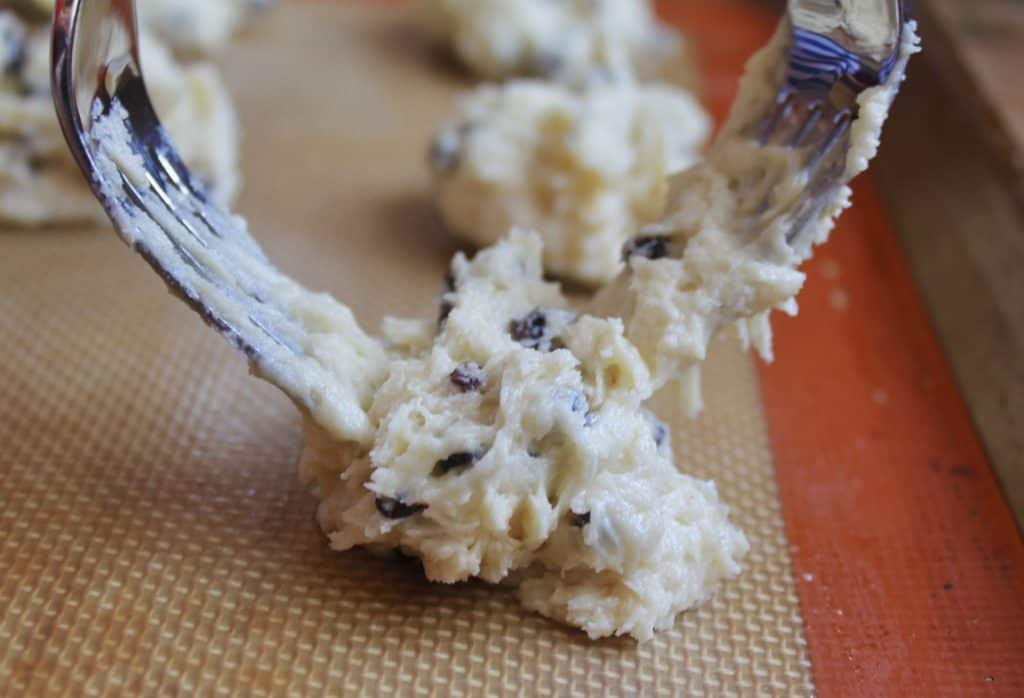 Forming rock cakes on a baking tray using forks to create their signature rough, rocky appearance