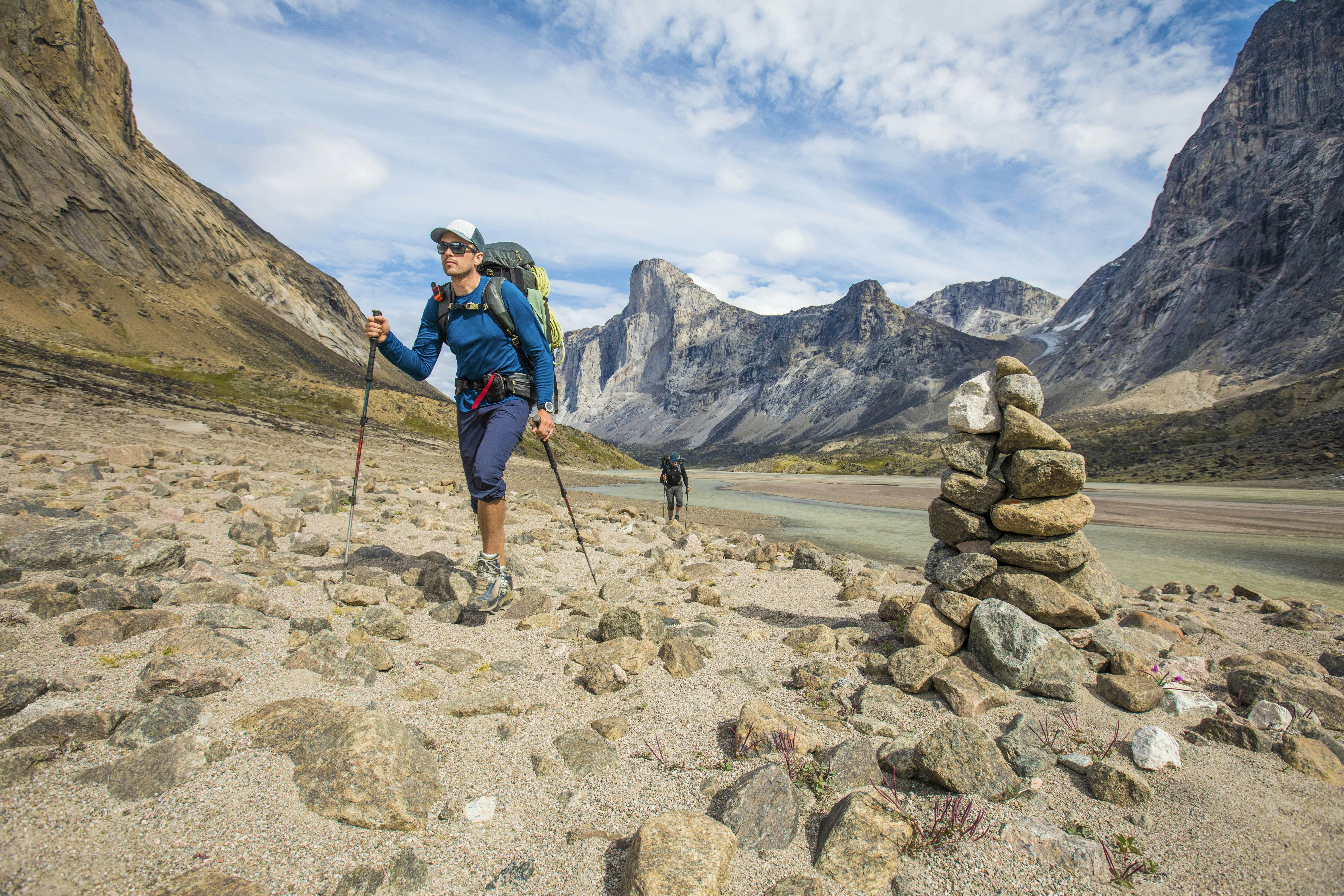 Backpackers hike past cairn, marking the trail