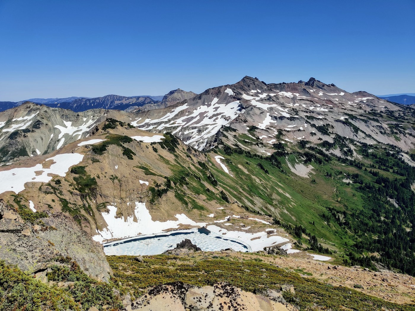 Goat Lake trail in Goat Rocks Wilderness featuring a hiker at a pristine alpine lake surrounded by rocky terrain