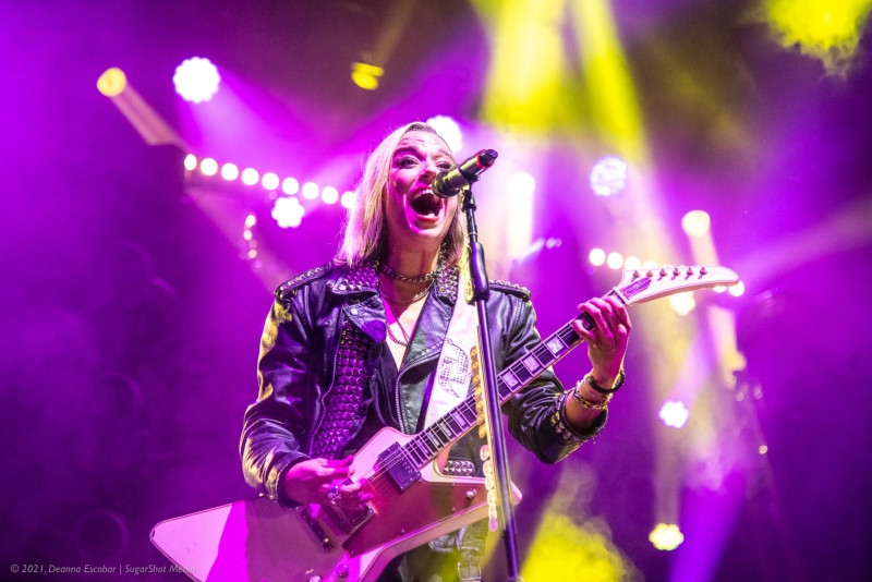 Lzzy Hale of Halestorm captivating the crowd at Blue Ridge Rock Festival Day 1. The Halestorm frontwoman is singing powerfully into the microphone, bathed in stage lights.