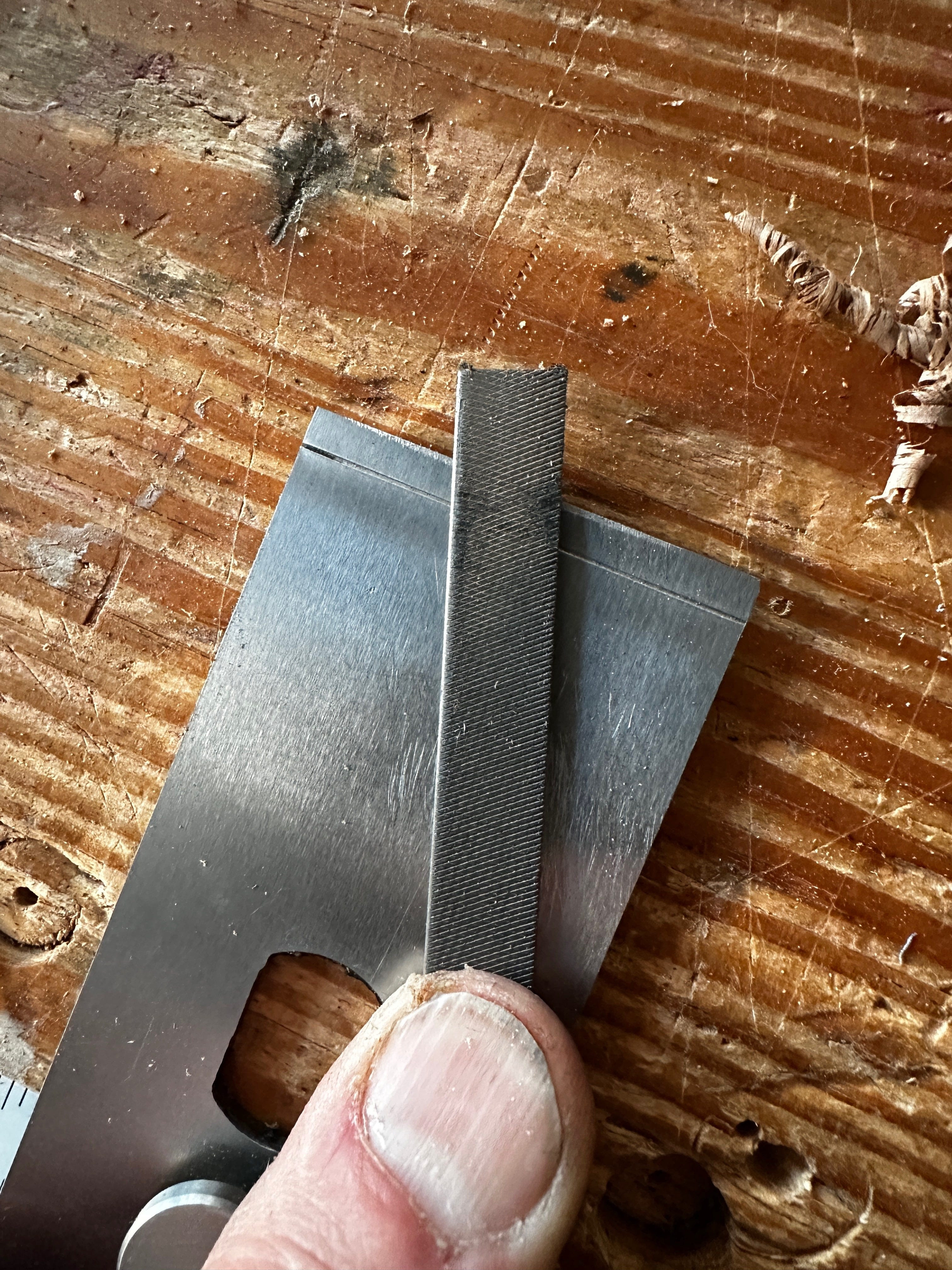 alt text: Filing the underside of the chipbreaker to ensure a proper fit with the bed rock plane iron.