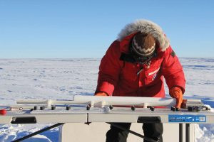 A scientist in Antarctica preparing a freshly extracted ice core for transport, highlighting the field work involved in ice core research.