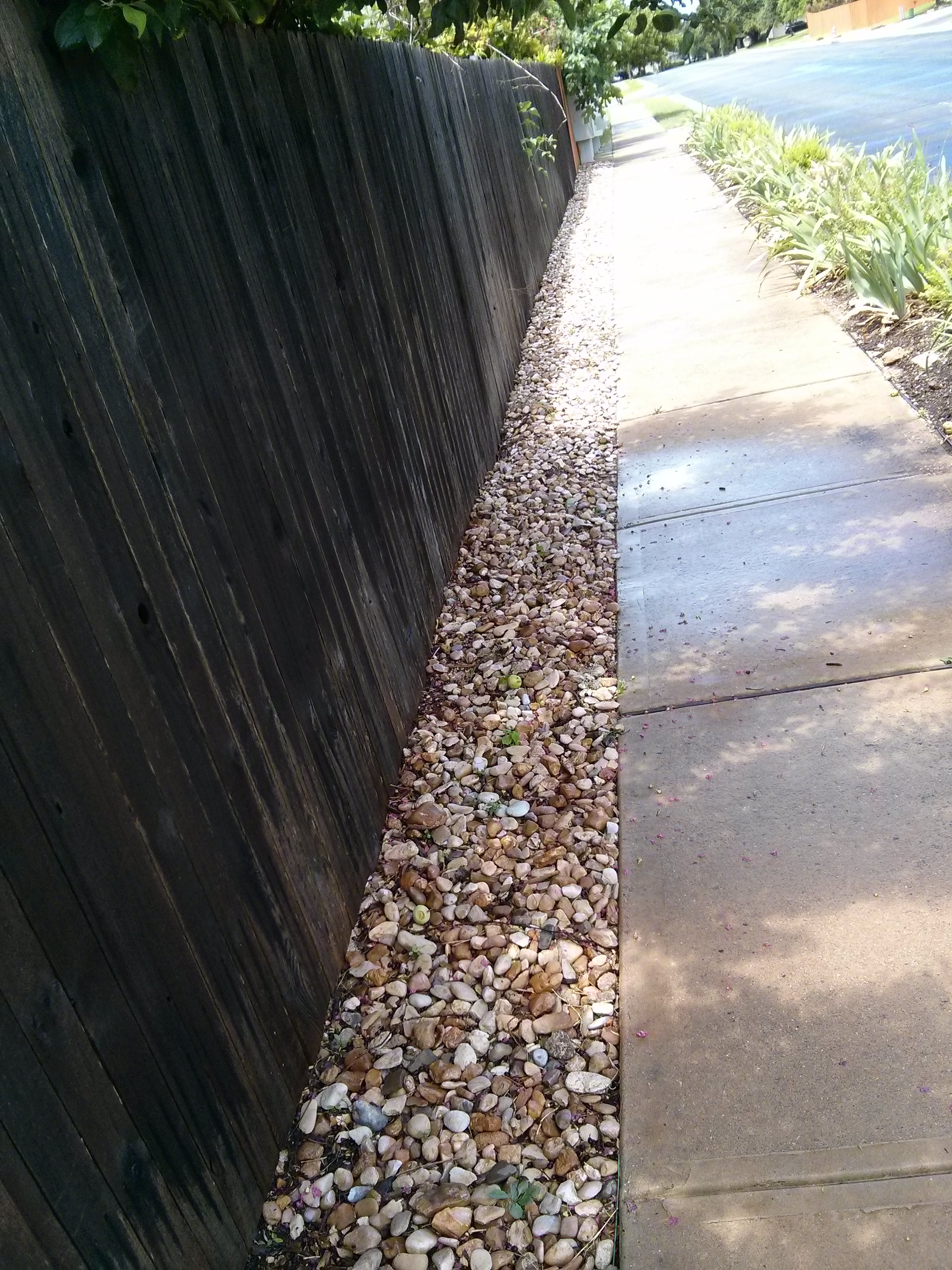 River rock used in a narrow side yard, creating a low-maintenance and visually appealing strip along the fence.