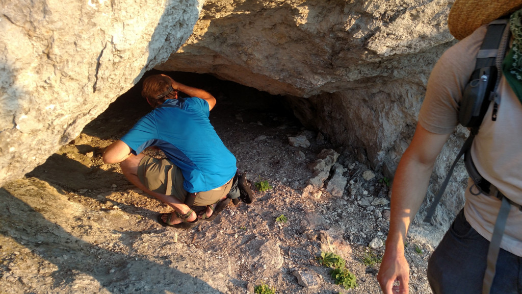 A hiker peering into a small cave along the Frog Rock trail.