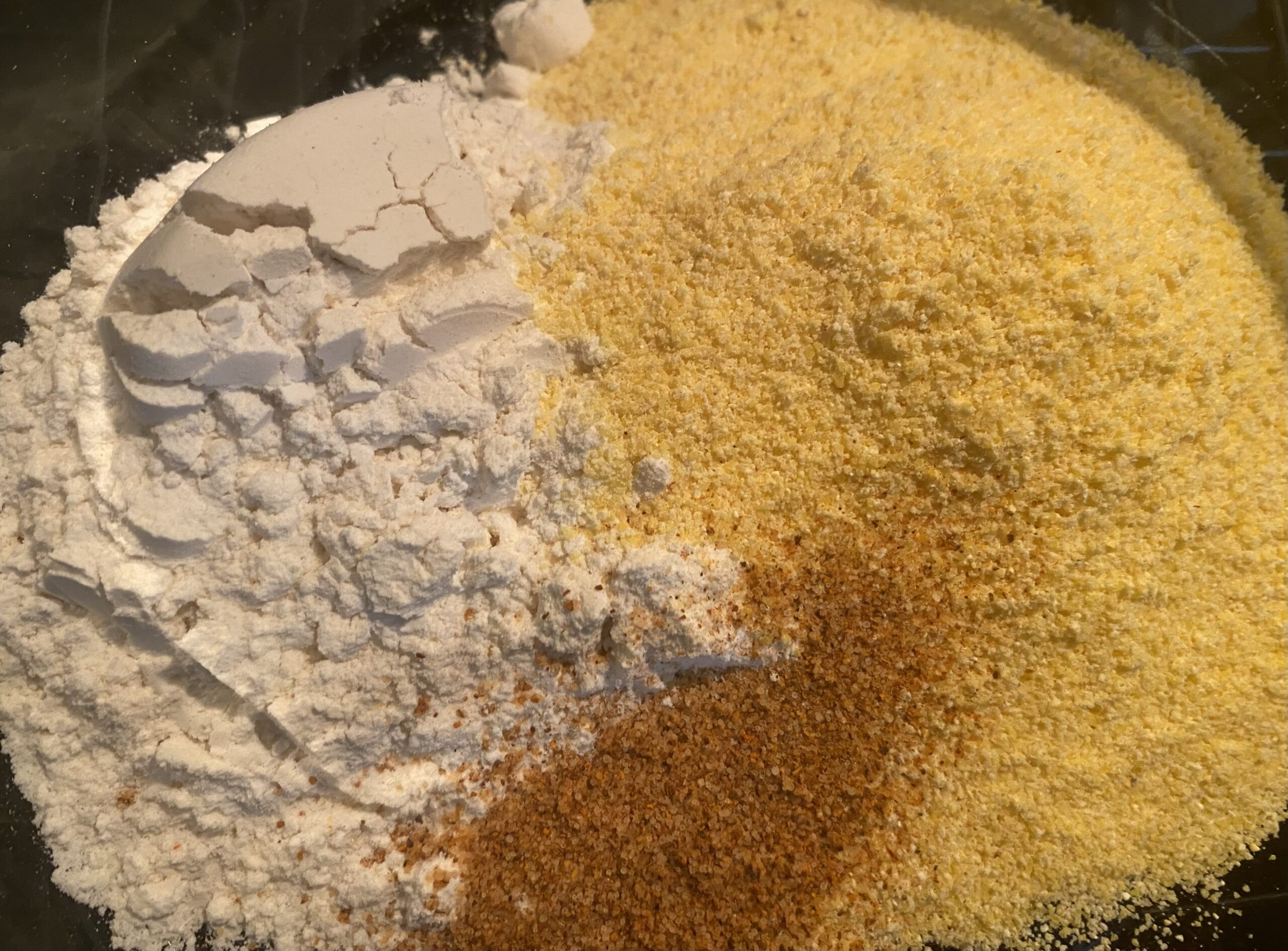 Rock fish fillets being shaken in a paper bag with cornmeal breading.