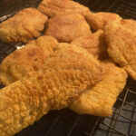 Platter of golden brown Southern fried rock fish, ready to serve.