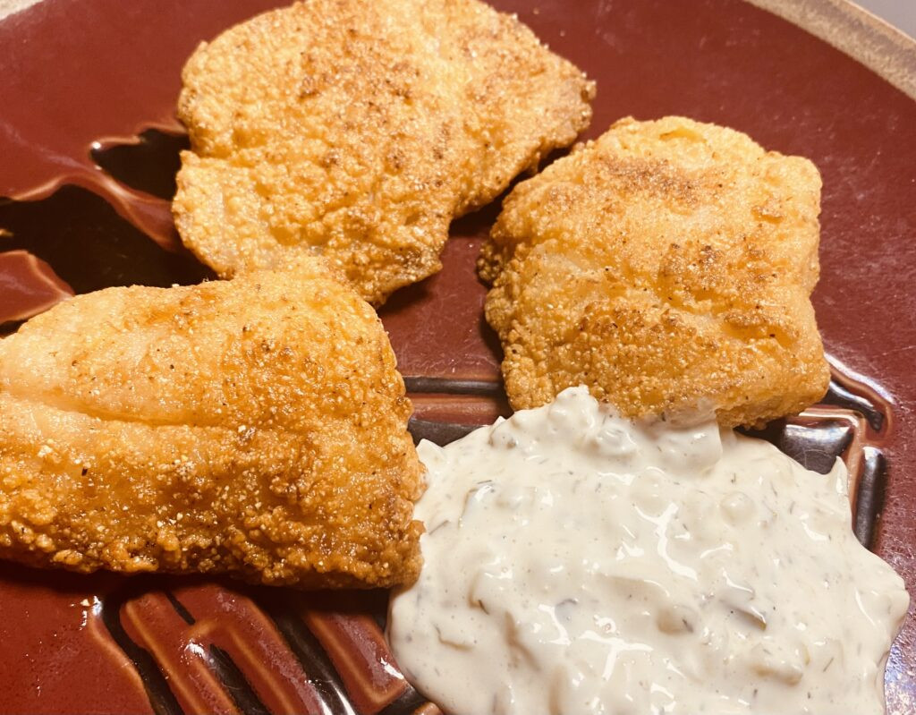 Close-up of rock fish fillets coated in cornmeal, highlighting the crispy texture.