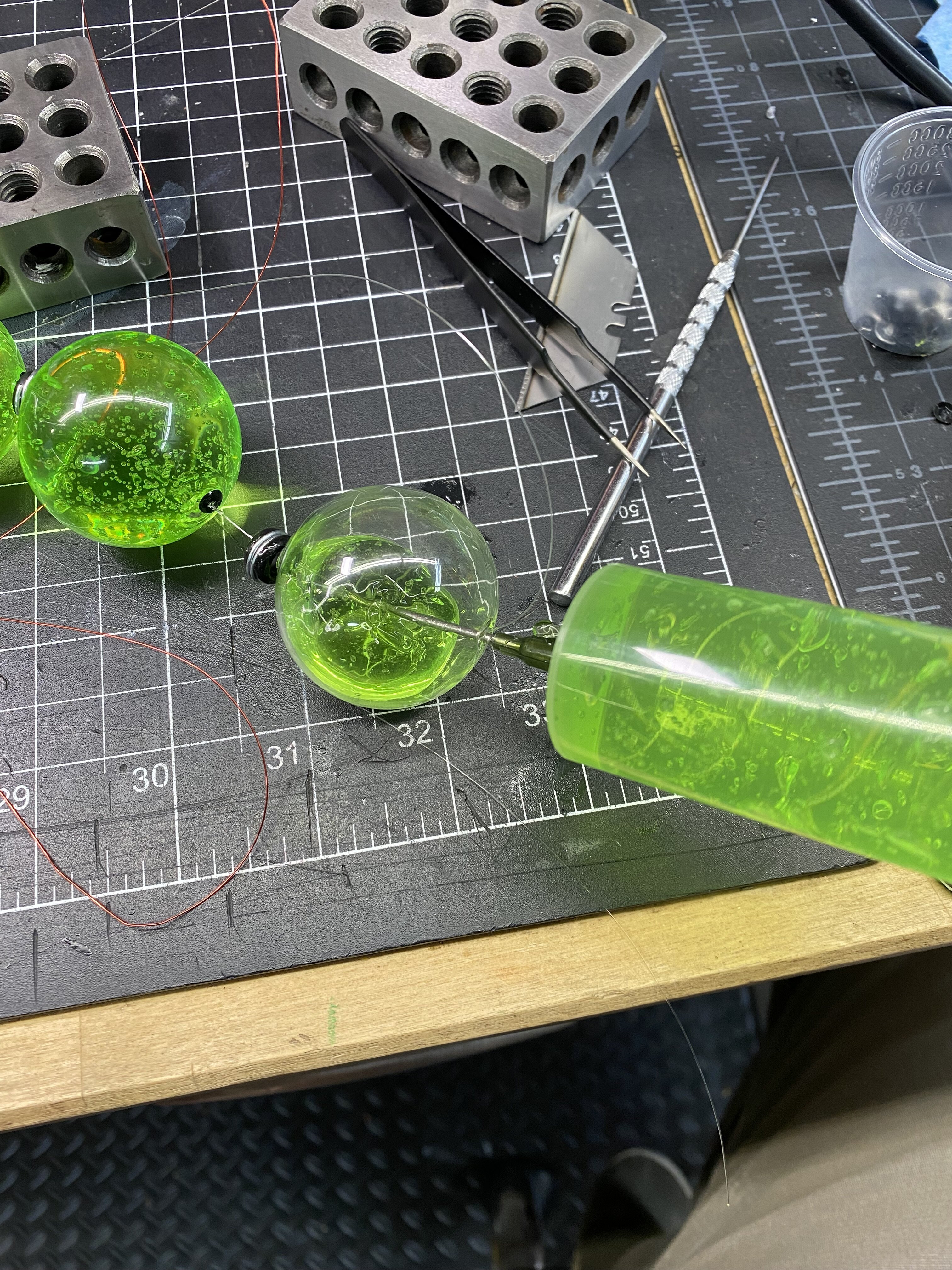 Process of filling glass pearls with green gel using a syringe for VX canister prop