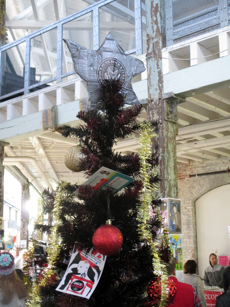 A fake Christmas tree decorated with punk rock themed items at the center of the flea market.