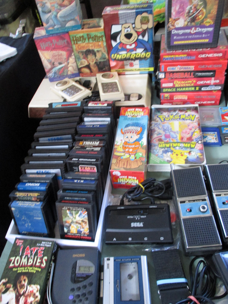 A collection of 1980s media and gaming consoles, including Atari games, VHS tapes, and a Walkman.