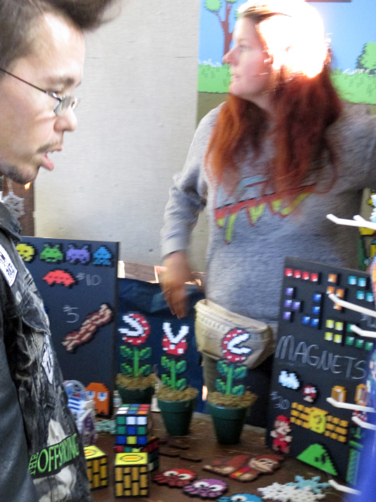 Perler bead art depicting 1980s pop culture icons displayed at a vendor stall.