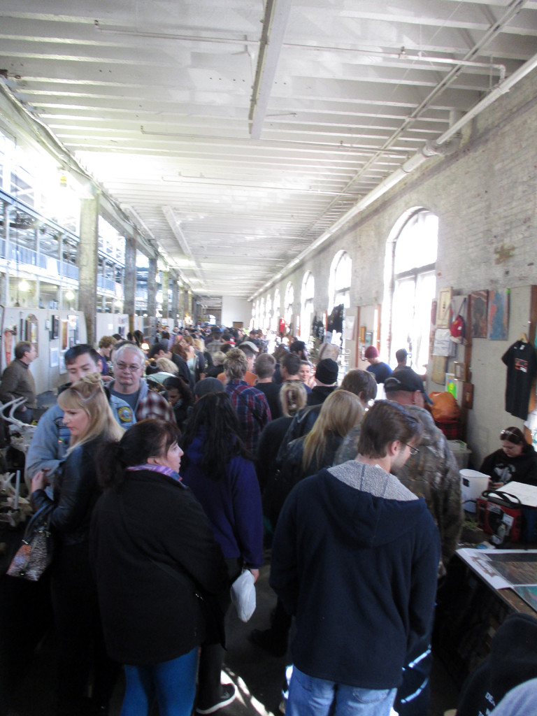 People walking through the vendor stalls at the Punk Rock Flea Market inside the Roebling Wire Works.