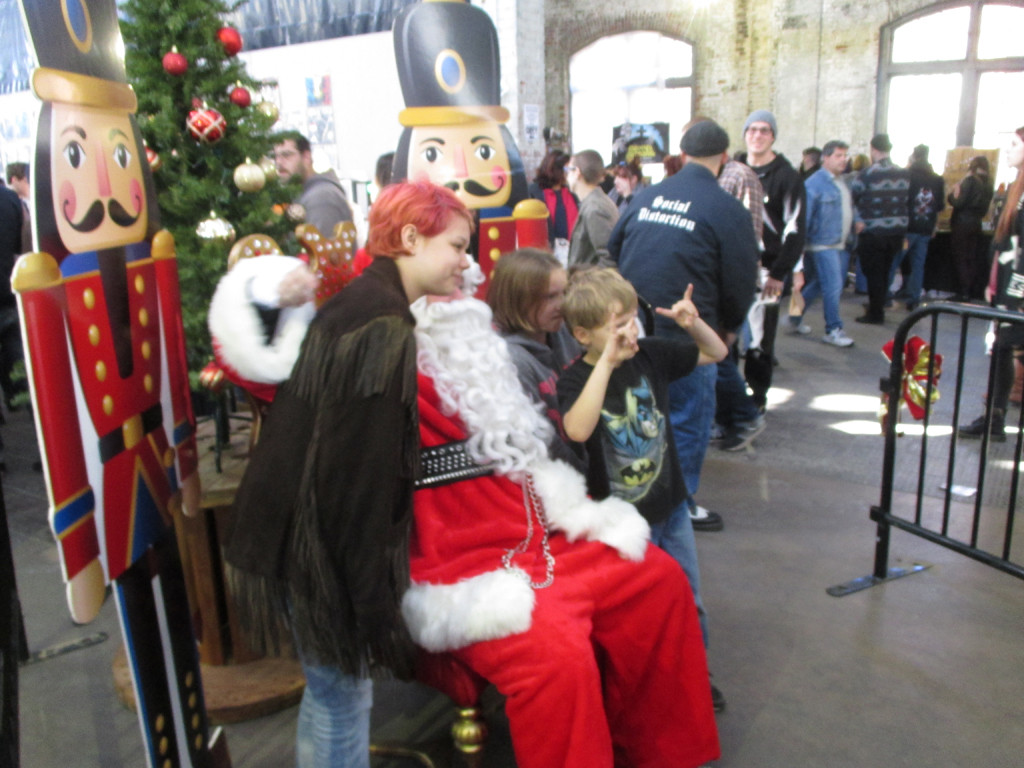 A person dressed as &quot;Punk Rock Santa&quot; wearing a studded belt and patched red coat.