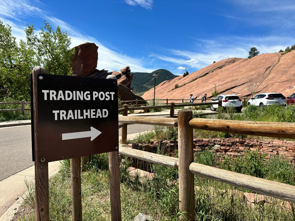 Wooden trail sign clearly marking the entrance to the Trading Post Trail at Red Rocks Park.