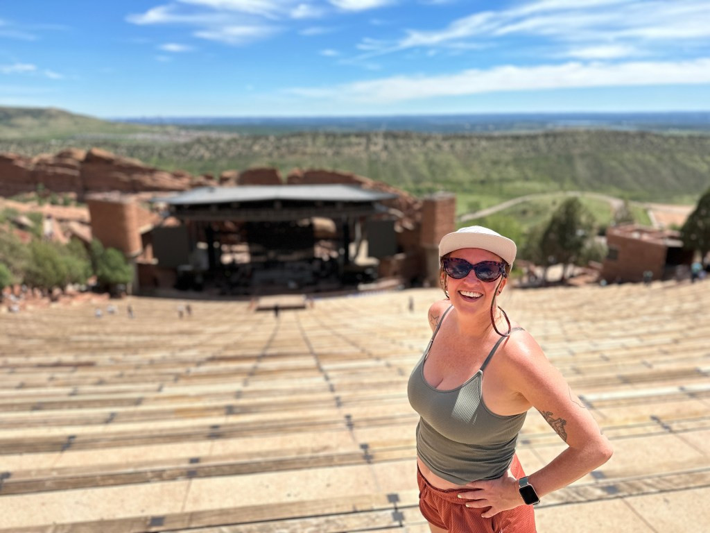 The author standing at the top of Red Rocks Amphitheater, overlooking the stage and Denver skyline.