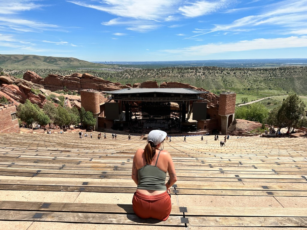 The author sitting at the top of Red Rocks Amphitheater, enjoying the view and emphasizing the reward after the hike.