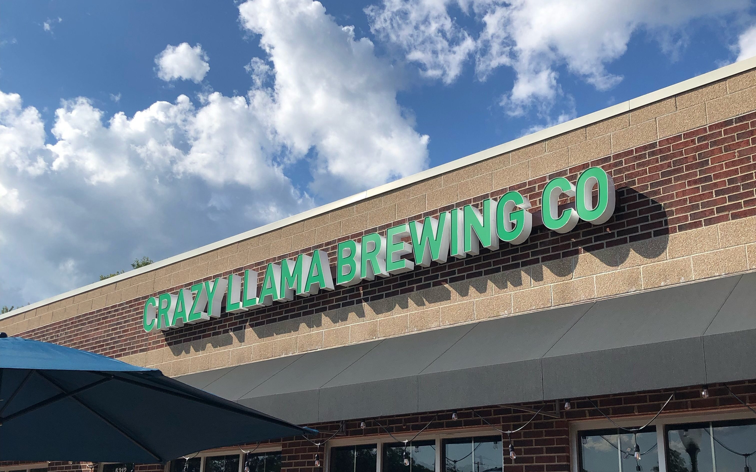 Exterior of Crazy Llama Brewing in Roscoe, IL, with outdoor seating and string lights