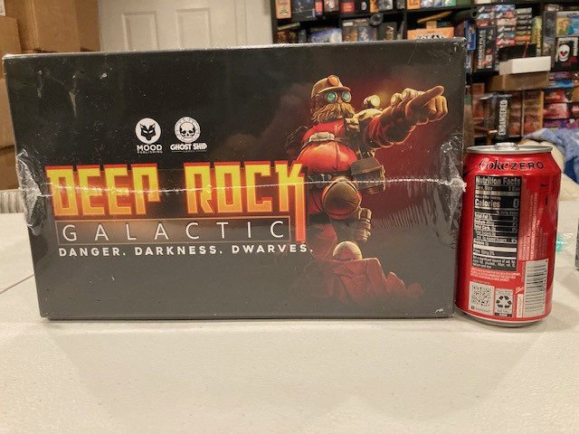 Deep Rock Galactic Board Game Box Next to Coke Can - Emphasizing the Large Box Size of Deep Rock Galactic Board Game