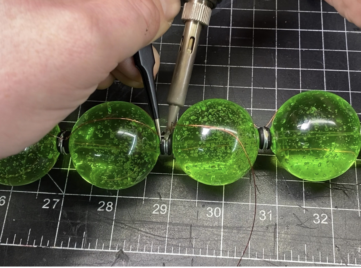 Soldering magnet wire to spacer rings on string of pearls for VX canister prop