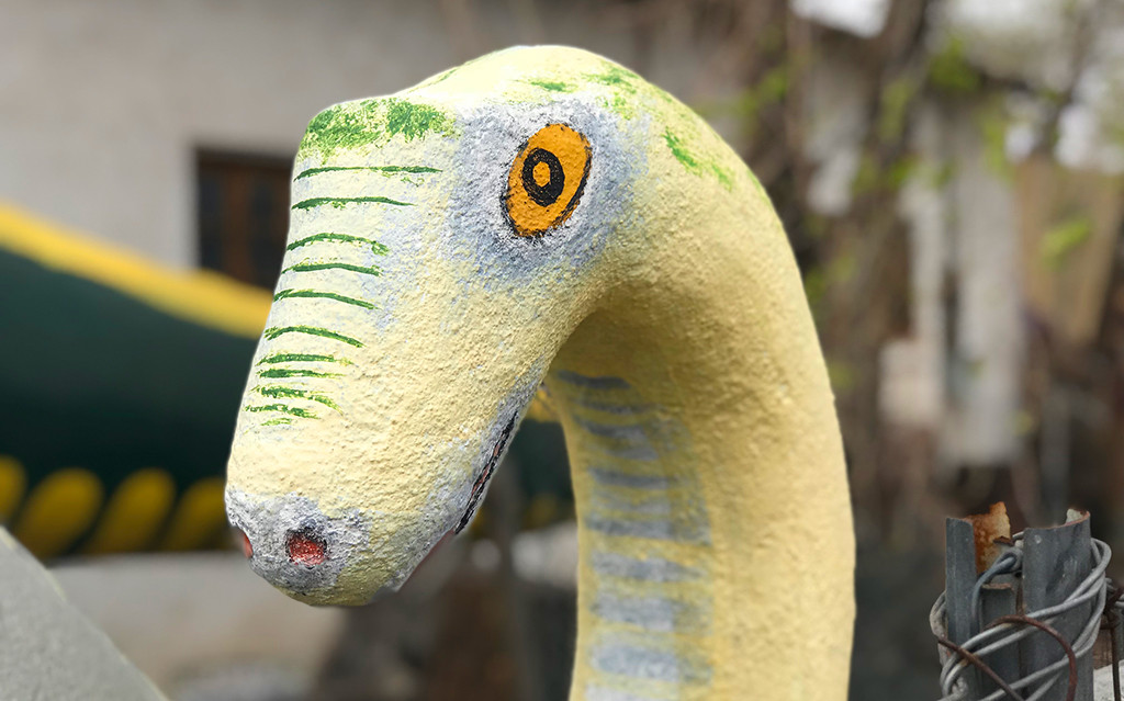 A detailed shot of a brown dinosaur statue at the Indian Rock Shop, highlighting its textured surface and classic design