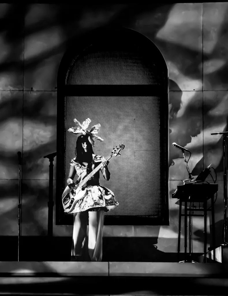 Khruangbin bassist Laura Lee performing at Red Rocks with dove headpiece and signature stage presence.