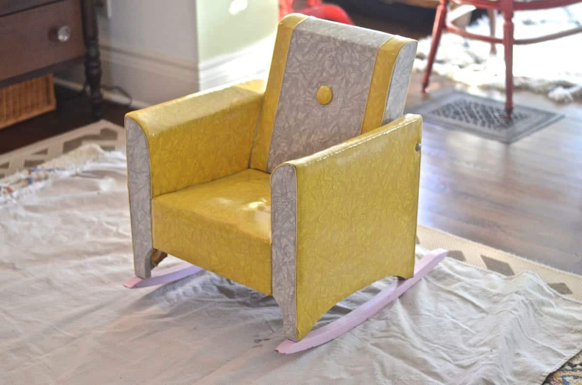 Dated kids rocking chair before reupholstering, showing worn fabric and wooden frame.