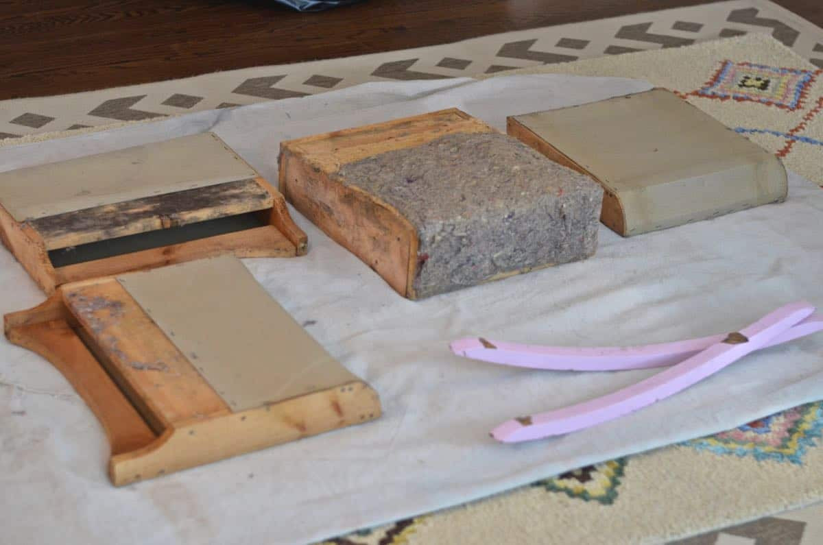 Rocking chair frame with old fabric and batting removed, revealing the bare wood structure.