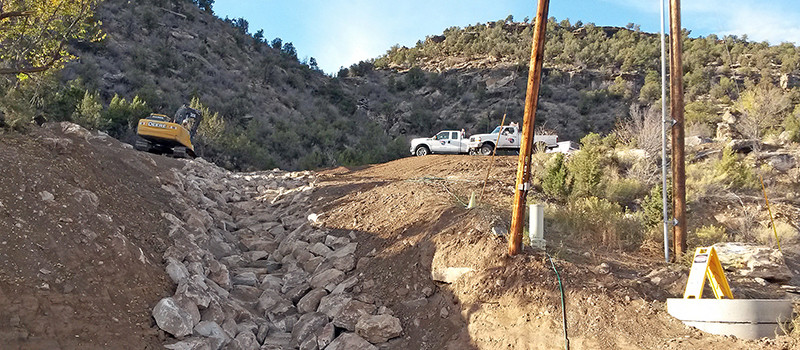 Partially grouted rip rap rocks used for slope stabilization in a drainage system