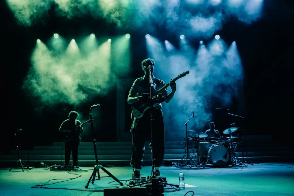 Wide shot of Peter Cat Recording Co. performing on the expansive Red Rocks stage to a growing crowd.