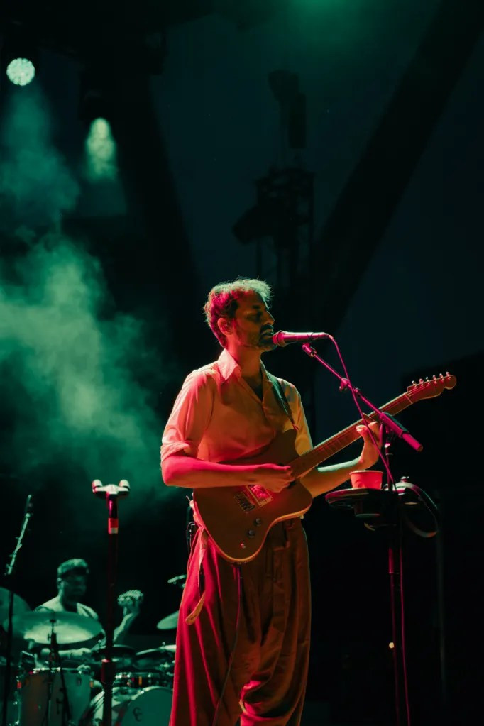 Peter Cat Recording Co. lead singer Suryakant Sawhney performing live at Red Rocks Amphitheatre, wearing harem pants and Salomon hiking boots.