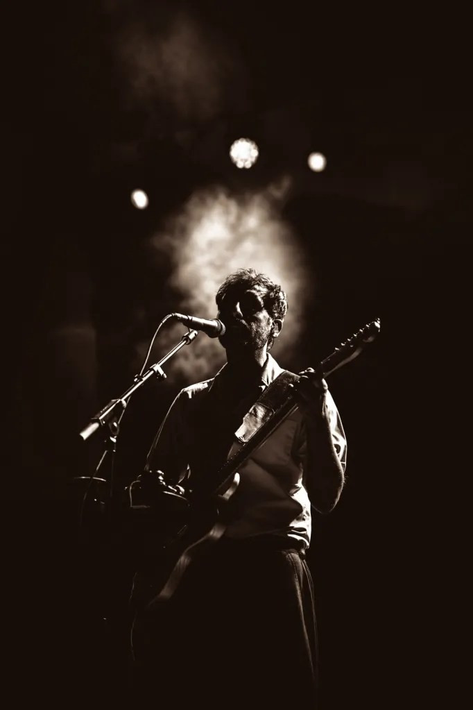 Peter Cat Recording Co. band members performing on stage at Red Rocks, bathed in warm stage lights.