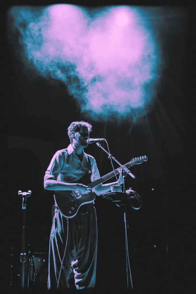 Peter Cat Recording Co. keyboardist immersed in their performance at Red Rocks, with the audience visible in the background.